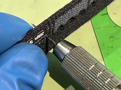 専用工具でベルトに穴を開けている作業