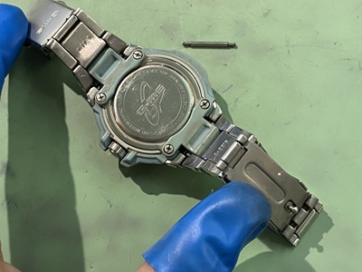 ベルトピンを抜き、時計本体をフラットにしてから裏蓋のネジを緩める様子