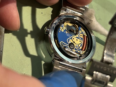 綿棒を使い、ムーブメント周辺の微細な汚れを外側へ吐き出すように掃除する様子。