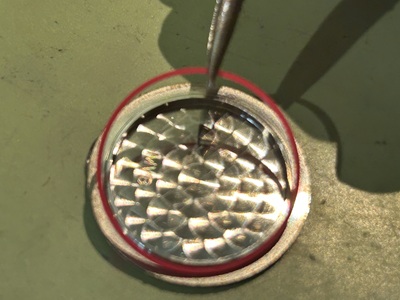 ピンセットでケースから細いゴムパッキンを取り外している様子。