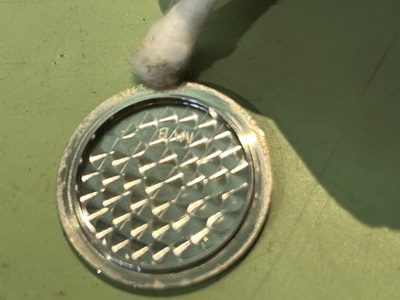 裏蓋の溝を綿棒でなぞるように掃除している様子。