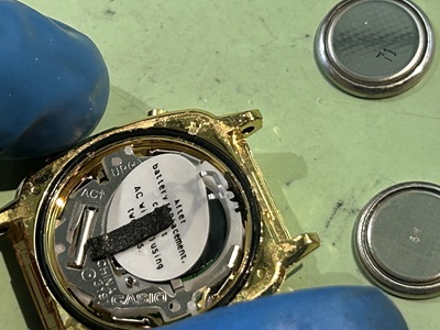 裏蓋が開けられ、古い電池が露出した時計の内部構造。