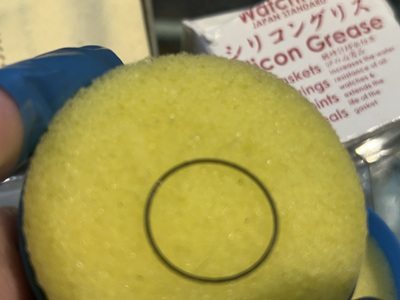 ピンセットで保持したパッキンにシリコングリースを塗布する様子。