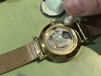 開封された時計内部のムーブメントを綿棒で清掃する様子