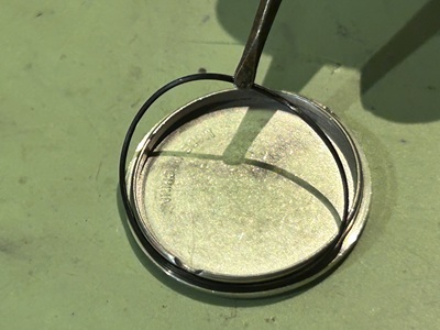 時計の裏蓋から細いゴムパッキンを取り外す様子