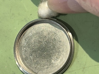 裏蓋の縁に付着した汚れを綿棒でクリーニングする様子