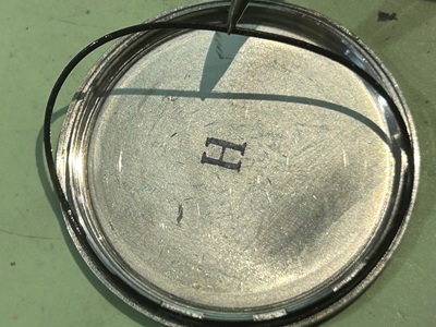 ピンセットで裏蓋のパッキン（ゴムリング）を外す様子。