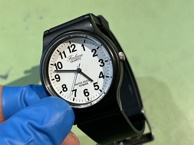 白い文字盤に力強いアラビア数字が並ぶ、シチズン・ファルコンの腕時計。秒針が停止している。