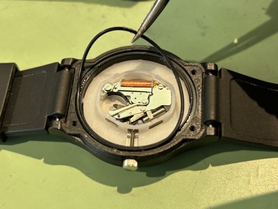 ピンセットを用いて、細い黒色のゴムパッキンをケースから取り出している様子。