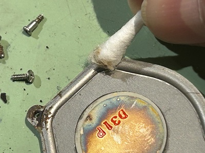 綿棒で金属製の裏蓋の縁を掃除している様子。