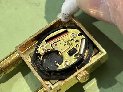 開いたケースから古い電池を取り除き、ムーブメント周りを清掃している様子。
