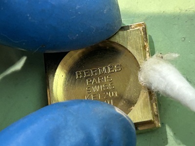 ピンセットで裏蓋の非常に細かな隙間の汚れを書き出している接写写真。