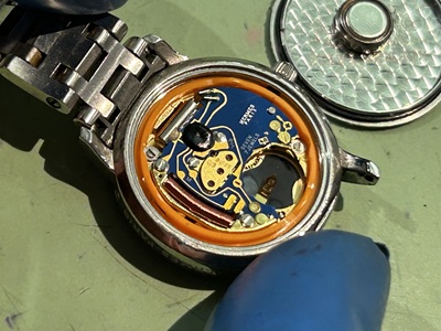 エルメスの裏蓋を開け、古い電池を取り出している時計修理の様子。