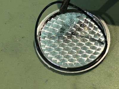 ピンセットでパッキンの劣化状態をチェックしている時計の内部。