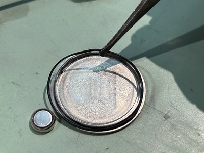 ピンセットで裏蓋のパッキンを取り出し、状態を確認する様子。