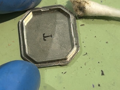 綿棒を使い、裏蓋の溝に溜まった黒い汚れを拭き取っている様子。