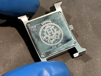 電池交換作業のために本体ケースから丁寧に取り外されたエルメスの長いレザーベルト