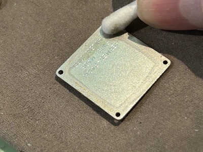 綿棒を使ってエルメスのロゴが刻まれた金属製の裏蓋の内側を綺麗に掃除する様子