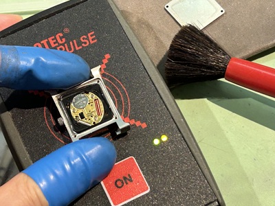 新しい電池をセットしパルスチェッカー（測定器）に乗せて正常動作を確認している様子