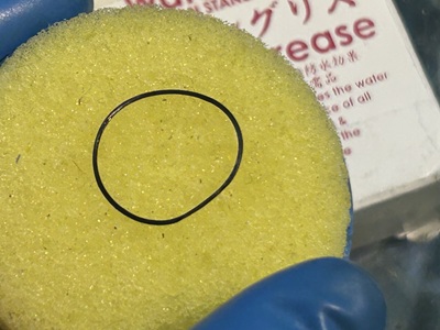 丸いスポンジの上に置かれた、グリース処理されたパッキン。