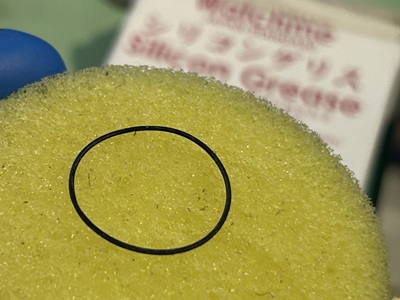 取り外したゴムパッキンを透明なシリコングリース塗布器に入れ、防水処理を施している様子。