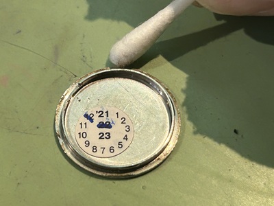 パッキンを外した裏蓋の溝。綿棒の先に黒い蓄積汚れが付着しているお掃除の様子。