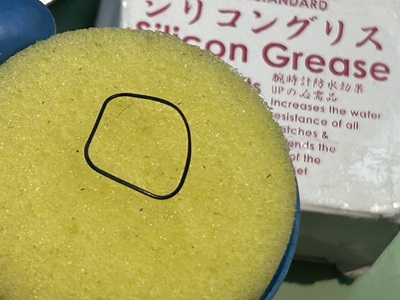 黄色のスポンジの上に乗ったゴムパッキンとシリコングリースの箱