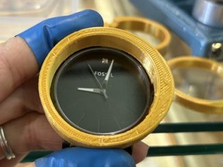 時計の周りにぴったりとはまった、3Dプリンタ製の黄色い円形の工具