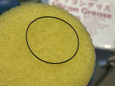 専用のグリース含浸器（スポンジ）を使い、新しい輪状のパッキンにシリコングリースを塗布している様子。
