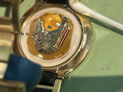 裏蓋を開けて綿棒で清掃する様子