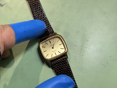 ゴールドの薄型ケースに、ゴールドの文字盤と黒いバーインデックスを配したオメガ（OMEGA）のクォーツ腕時計。