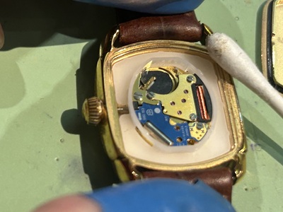 綿棒を使用してハミルトンの腕時計内部の電池格納部分を丁寧に掃除する職人の手元