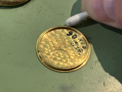 綿棒と工具を使用して腕時計の裏蓋の溝に溜まった汚れを綺麗に掃除する工程
