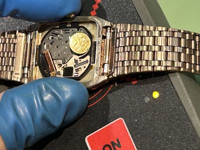 新しい電池をセットした時計をパルスチェッカーに載せ、電子回路の動作信号と針の動きを確認している様子