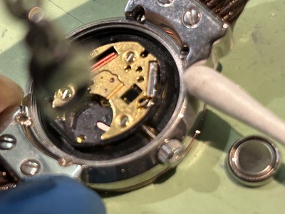 綿棒を使用して裏蓋を開けたシャリオールの腕時計内部を優しく清掃する時計職人の手元