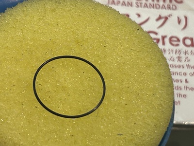 防水性を蘇らせるために専用の黄色いグリーススポンジの上に置かれた腕時計用パッキン