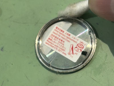 ステンレス製の裏蓋のフチや内側の溝の部分を、綿棒を使って細かく清掃しているメンテナンスの様子