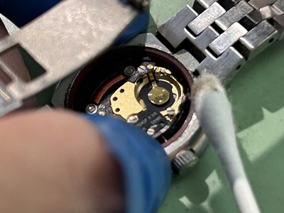 綿棒を使用して腕時計の電池格納部分とその周辺の汚れを掃除する様子