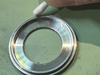 パッキンを取り外した裏蓋の溝に溜まった汚れを綿棒で掃除する様子