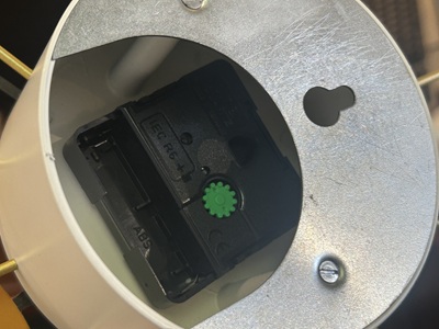 掛け時計の裏側にある黒いプラスチック製のクォーツムーブメント