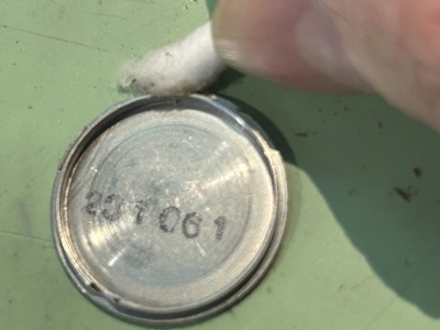 裏蓋の金属プレート内側、パッキンが密着していた部分の汚れを綿棒で掃除する様子