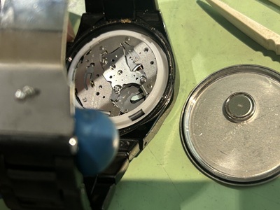 スクリューバックの裏蓋を開封し、白いプラスチック製の保持スペーサーに囲まれた金属製のクォーツムーブメントが現れた状態