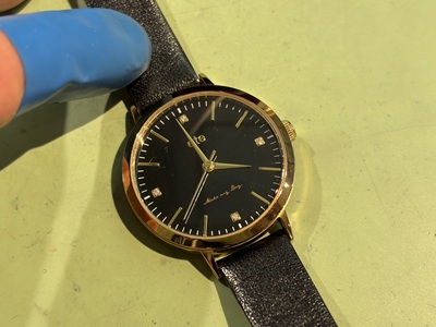 指サックをつけた指でeteの腕時計を持ち、斜めから文字盤を写した写真