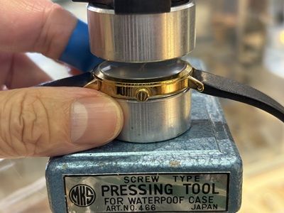 専用の圧入機(MKS製 PRESSING TOOL)に時計をセットし、裏蓋を閉め込んでいる様子