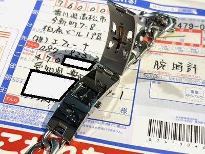 エファーナ宛てのゆうパック伝票の上に置かれた、フロントカバーが開いた状態のFICCEのメタルブレスレット腕時計