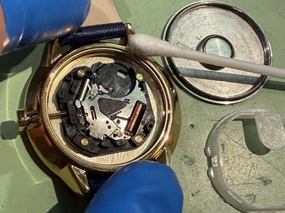 裏蓋を開けて内部ムーブメントの周りを綿棒で掃除する様子
