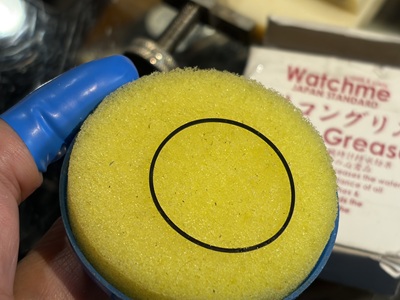 イエローのスポンジ型塗布器でゴムパッキンにシリコングリースを馴染ませる様子