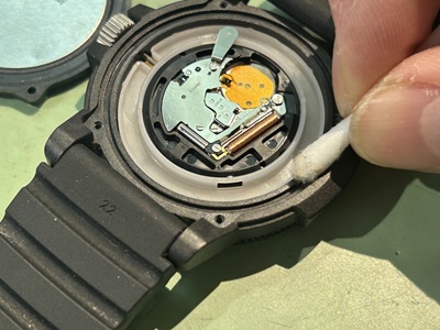 綿棒を用いてケース縁を掃除し、新しい電池をセットした様子