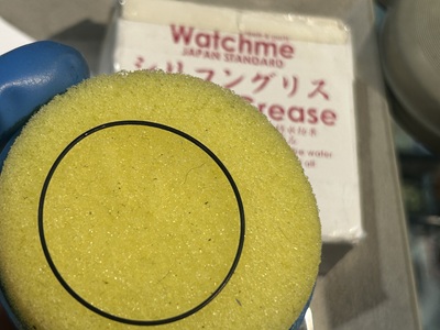 イエローのスポンジに挟んでゴムパッキンへシリコングリースを塗布する様子