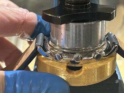3Dプリンター製の治具と時計をプレス機の下に置き、上部から金属プレスを当てて裏蓋をゆっくり閉めている様子